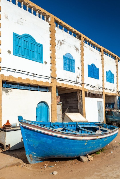 Um barco azul está no chão em frente aos edifícios da vila de pescadores de Tafelney