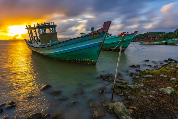 Um barco de pesca ancorado na costa em um belo nascer do sol.