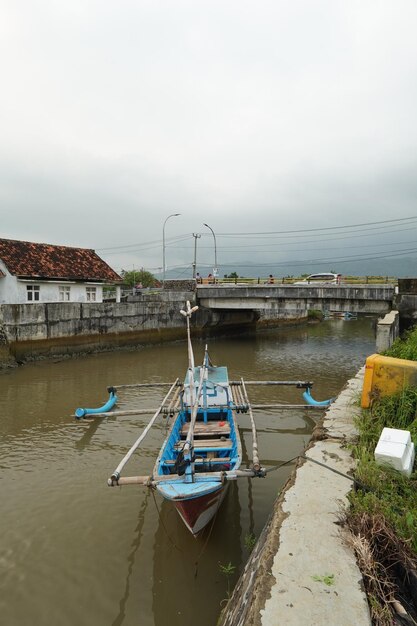 Um barco em um canal com uma casa ao fundo.