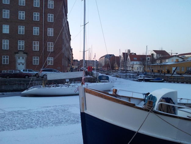 Um barco está atracado na água com a neve no chão.