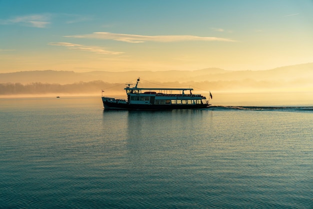 Foto um barco está navegando em um lago calmo ao pôr do sol