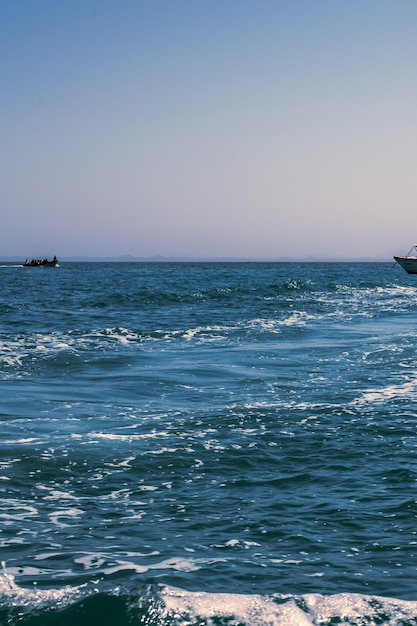 Um barco está navegando no oceano com um barco ao fundo.