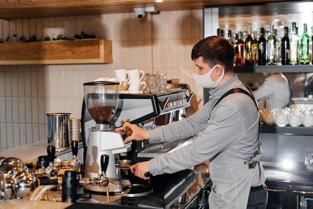 Um barista mascarado prepara um delicioso café requintado no bar de uma cafeteria o trabalho de restaurantes e cafés durante a pandemia