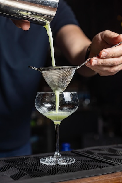Um barman servindo um coquetel em um copo