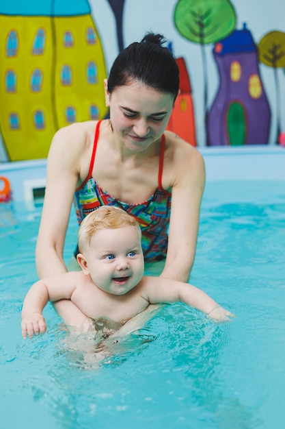 Um bebê aprende a nadar em uma piscina com um treinador Um bebê aprende a nadar Desenvolvimento da criança