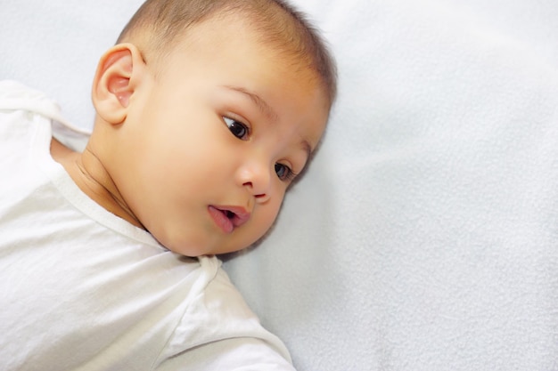 Um bebê asiático fofo deitado na cama azul O conceito de empatia de cuidado adorável fofo adorável
