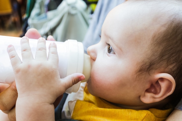 Um bebê bebendo mamadeira com os olhos abertos