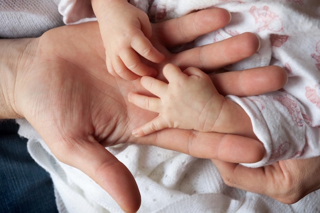 Um bebê coloca as mãos na mão de seu pai