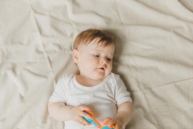 Um bebê com um mordedor e um chocalho em uma cama de algodão Dentição Espaço para cópia do artigo infantil