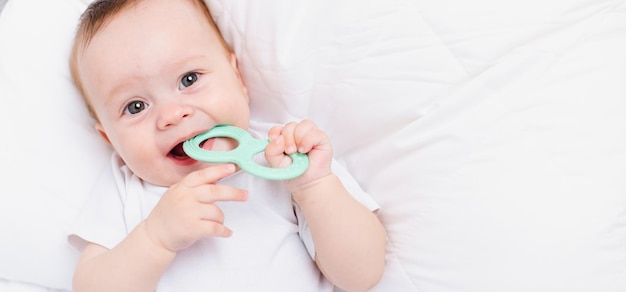 Um bebê com um mordedor em um fundo branco Dentição Artigo infantil