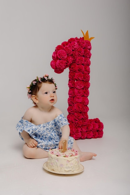 Foto um bebê com uma flor no cabelo e a letra l à esquerda