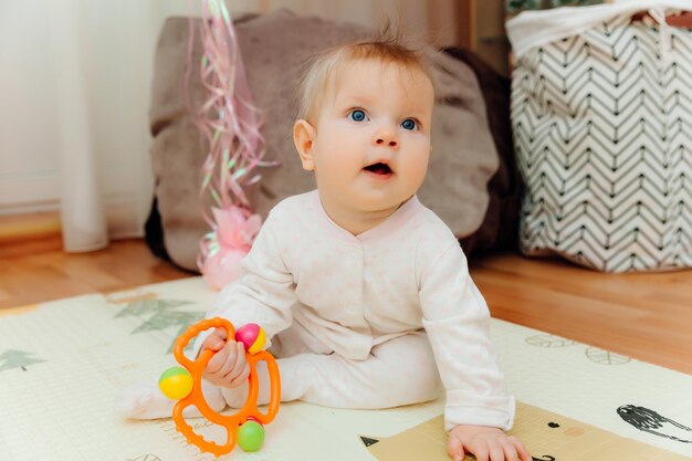 Um bebê de seis meses brinca no chão com brinquedos coloridos O bebê aprende a engatinhar retrato de um bebê de 6 meses