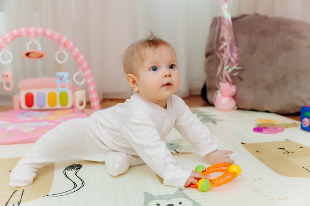 Um bebê de seis meses brinca no chão com brinquedos coloridos O bebê aprende a engatinhar retrato de um bebê de 6 meses