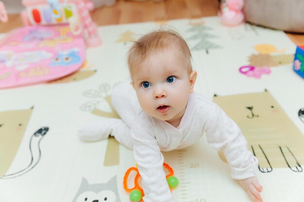 Um bebê de seis meses brinca no chão com brinquedos coloridos O bebê aprende a engatinhar retrato