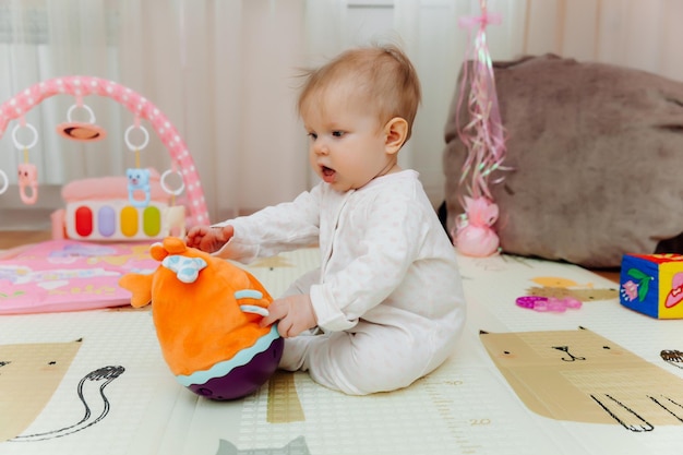 Um bebê de seis meses brinca no chão com brinquedos coloridos O bebê aprende a engatinhar retrato