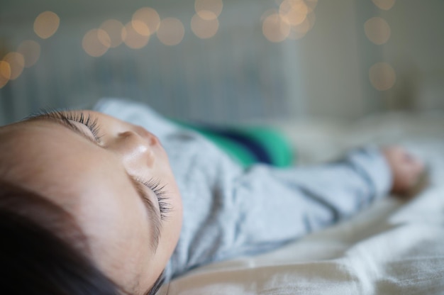 Um bebê dorme em um berço branco com uma meia verde na camisa.