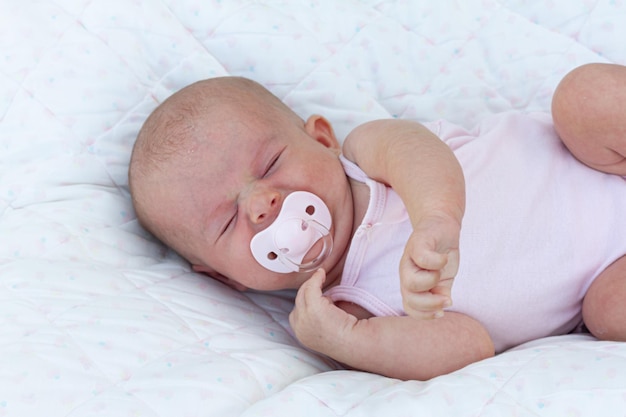 Um bebê dormindo com uma chupeta que diz 'baby'on it '