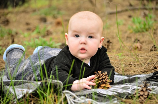 Um bebê em um campo com uma pinha