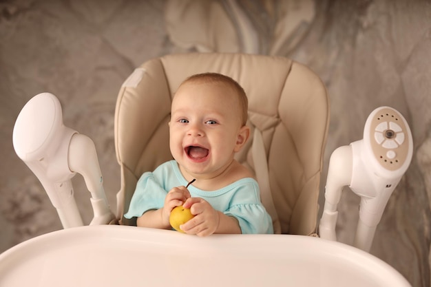 um bebê em uma cadeira de alimentação come uma pêra sozinha