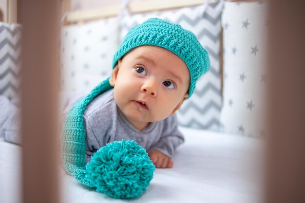 Um bebê engraçado em um chapéu engraçado está de bruços com a cabeça levantada