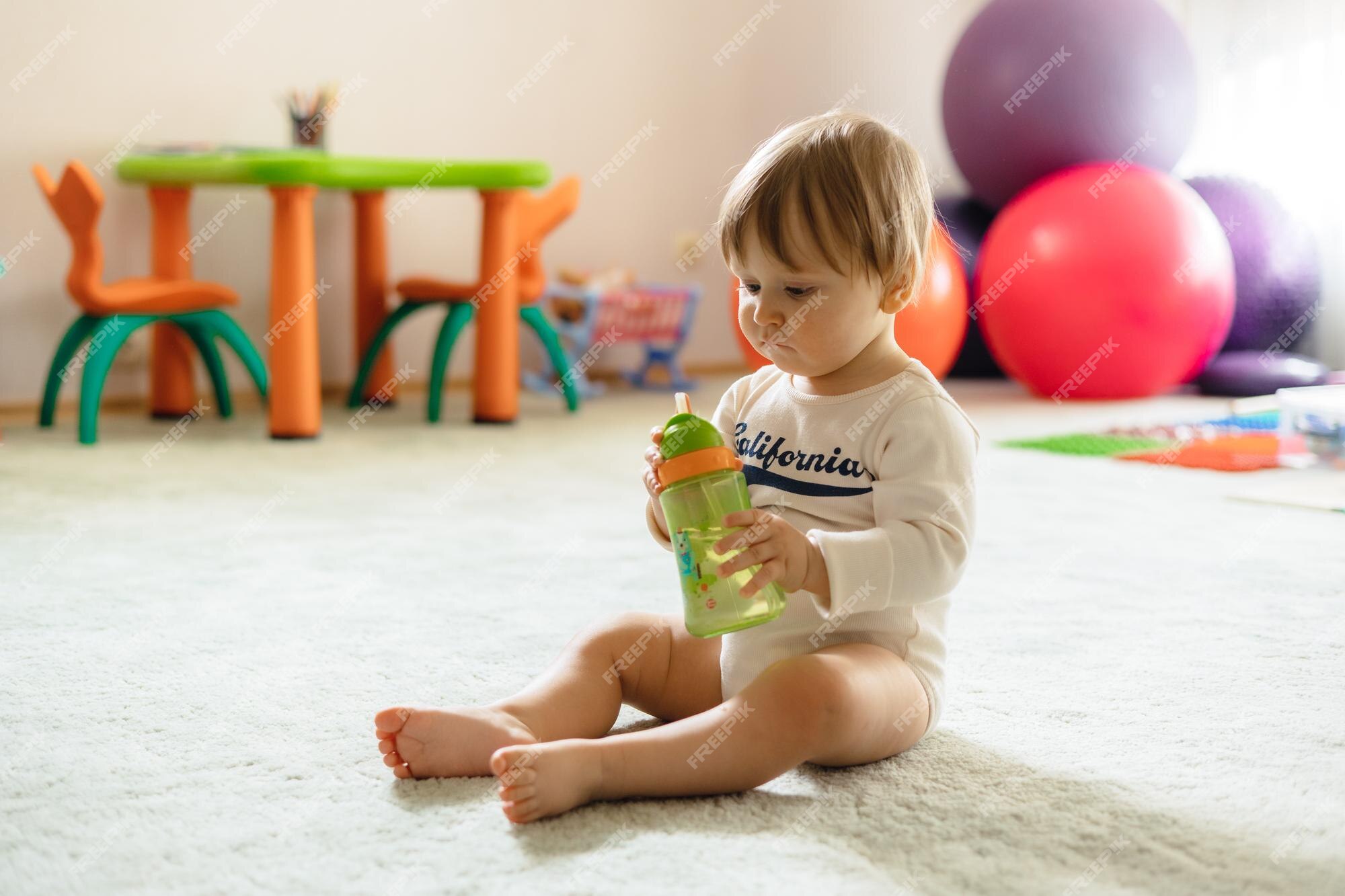 Mãe Ajuda Um Bebê Recém Nascido a Sentar. Criança Gritando Na Sala De Jogos  Em Um Chão De Espuma Mole Foto de Stock - Imagem de gritar, casa: 215291796