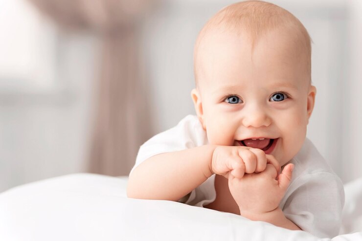Foto um bebê está sorrindo e tem as mãos no queixo