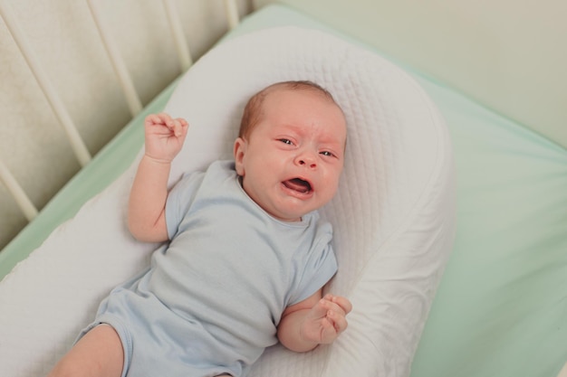 Um bebê faminto está chorando no berço Bebê chorando Emoções infantis Dor durante a dentição Uma criança faminta Cólica infantil no estômago