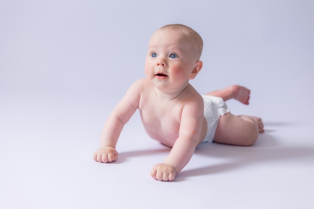 Um bebê fofo de 5 meses está deitado em uma fralda em um fundo branco no estúdio sorrindo e olhando para o quadro Baby39s health newborn baby space for text