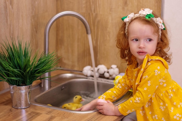 Um bebê para a Páscoa com patinhos amarelos Ao lado do bolo e ovos pintados Férias em família Felicidade