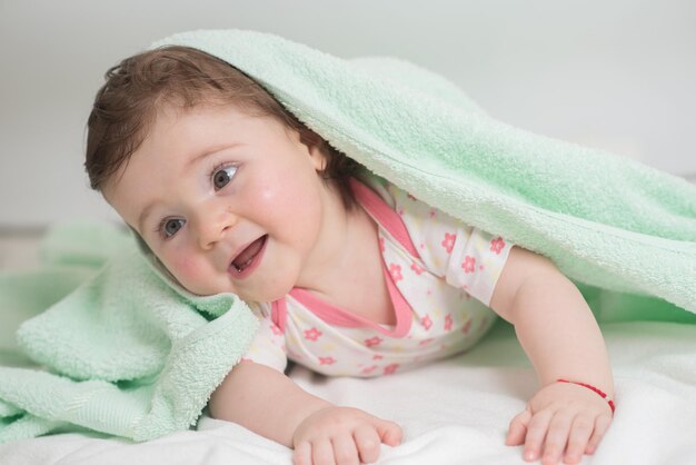 Um bebê pequeno está no banheiro coberto com uma toalha