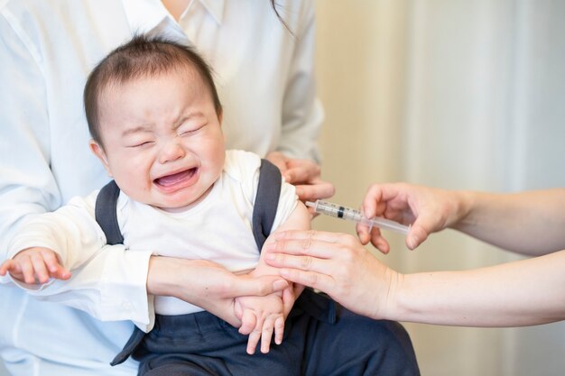 Um bebê que é vacinado enquanto é segurado pela mãe