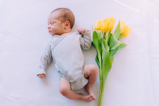 Um bebê recém-nascido com um buquê de tulipas 8 de março Bebê e flores Tulipas amarelas
