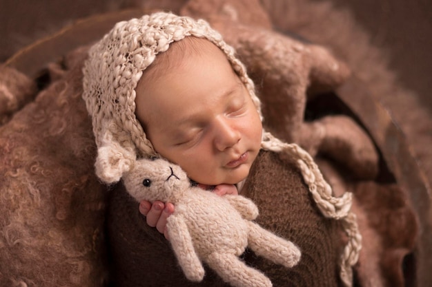 Foto um bebê recém-nascido de uma semana dormindo envolto segurando uma fotografia de recém-nascido de boneca