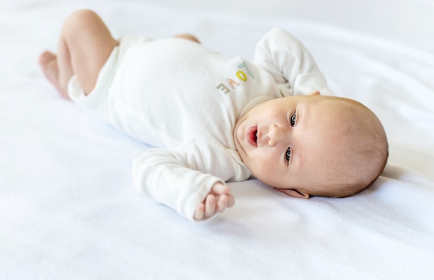 Um bebê recém-nascido deita em uma cama branca