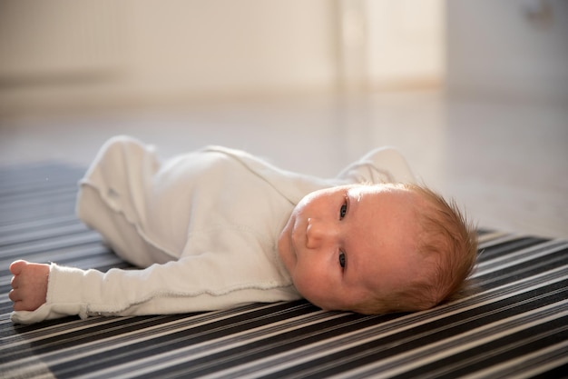 Um bebê recém-nascido deitado de costas na folha monocromática listrada