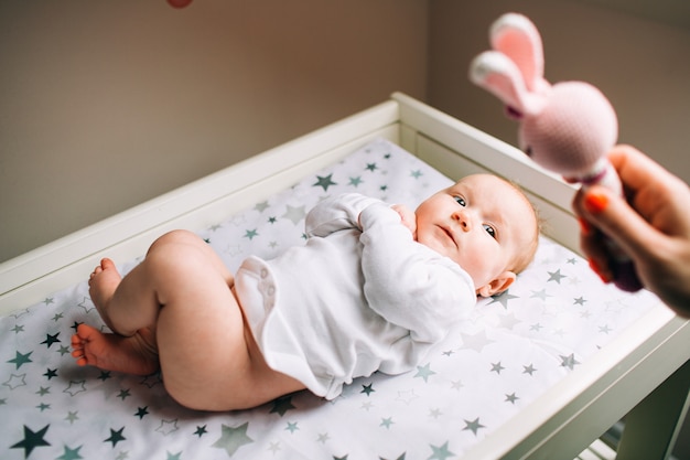 Um bebê recém-nascido e os pais são brincados com um brinquedo infantil. Uma criança encontra-se em um trocador. Os primeiros anos de vida.