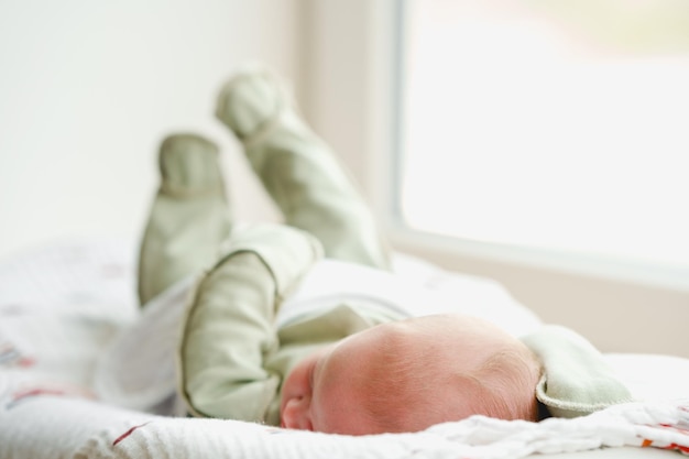 Um bebê recém-nascido está deitado em um casulo, o foco está nas pernas