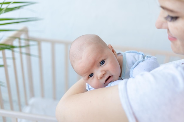 Um bebê recém-nascido nos braços de sua mãe perto do berço em casa amor dos pais e cuidado com o bebê nos primeiros dias após o nascimento
