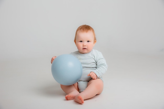 Um bebê segurando um balão azul na frente de um fundo branco