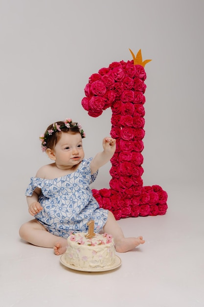 Foto um bebê senta-se na frente de um bolo com rosas nele