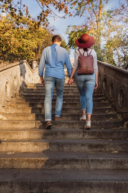 Foto um belo jovem casal de turistas está subindo escadas e olhando ao redor do castelo de buda em budapeste no outono