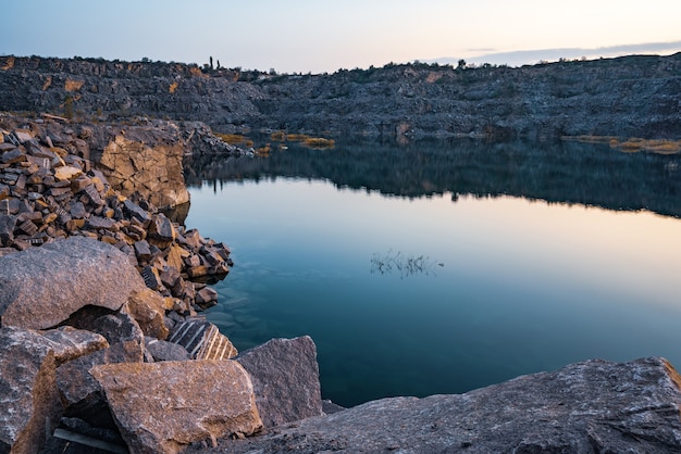 Um belo lago muito pequeno cercado por grandes pilhas de resíduos de pedra do trabalho duro na mina