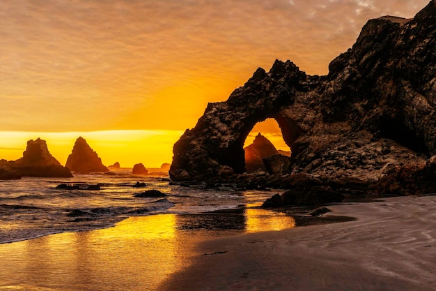Um belo pôr do sol sobre uma praia com um arco rochoso Playa Lobera Marcona Peru