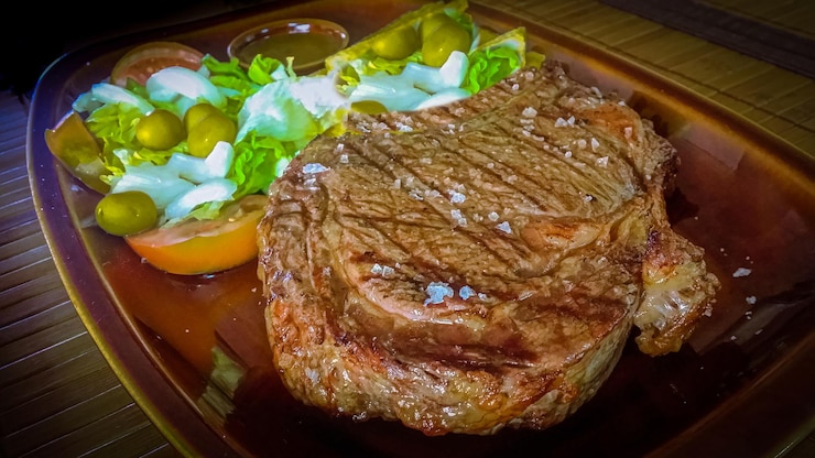 Foto um bife com um lado de salada e uma salada