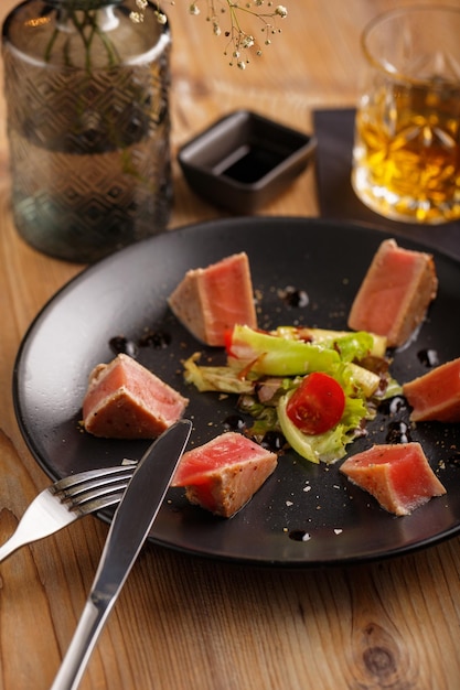 Um bife de salmão prato culinário em uma placa preta em um restaurante de mesa de madeira servindo