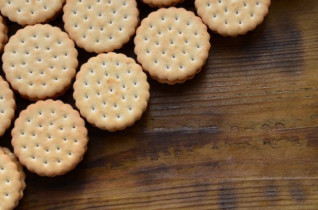 Um biscoito recheado redondo com recheio de coco encontra-se em grandes quantidades em uma superfície de madeira marrom