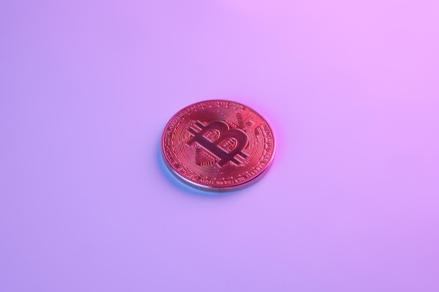 Um bitcoin dourado isolado em close-up de fundo rosa roxo com espaço de cópia