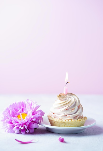 Um bolo com uma vela e uma flor em tons rosa suaves aniversário dia das mães