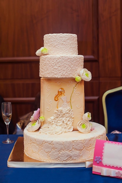 Um bolo de casamento branco de vários níveis em uma base de prata e flor rosa