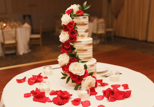 Um bolo de casamento com rosas vermelhas no topo